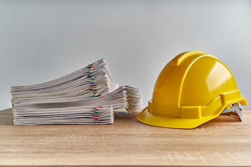 Stack overload document of report with yellow engineer hat