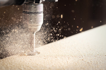 Drilling holes in a sheet of chipboard. Furniture assembly.