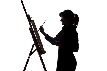 silhouette of a young woman painting on an easel on a white isolated background, the figure of a...