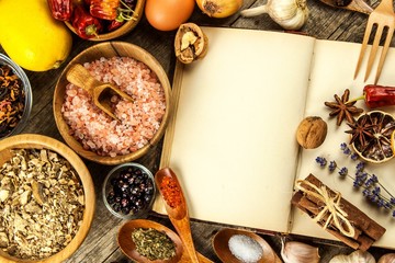 Cookbook and spice on a wooden table. Food preparation. An old book in the kitchen. Recipes for food