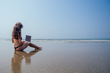 Fototapeta na wymiar copy space dream remote work,freedom and vacation concept.Woman freelancer working behind laptop sitting on the sand in on sandy beach background sea, blue sky and paradise landscape.solar block spf