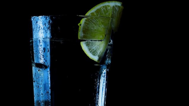 glass of water and lemon on black background