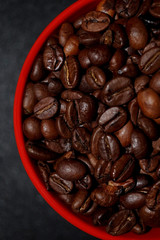 roasted coffee beans in red cup on a black background