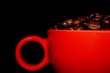 roasted coffe beans in red cup on a black background