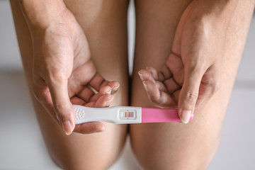 Young asian woman holding pregnancy test showing a positive result in bedroom, Wellness and healthy...