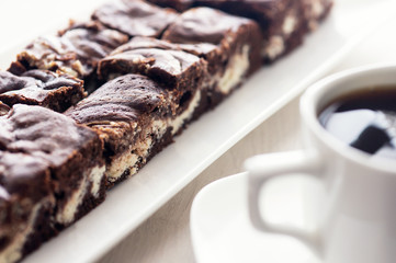 Chocolate brownie with a cup of coffee. High key.