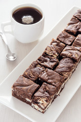 Chocolate brownie with a cup of coffee. High key.