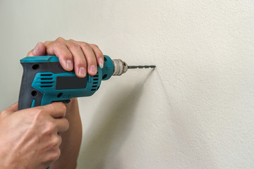 Asian man use electric drill on wall in him house, Copy space, Home improvement and repairs concept.