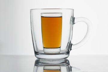 Small whiskey tank in a large transparent mug, visibility, deception close-up