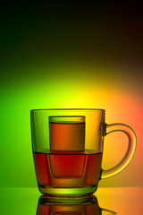 Refraction of liquid in glass, a glass in a mug of tea, on a colored background