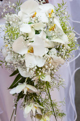 Beautiful wedding bouquet of white orchids in hands of the bride
