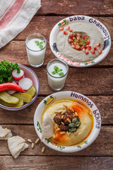 Hummus in traditional lebanon plate on a rustic table with vegetables