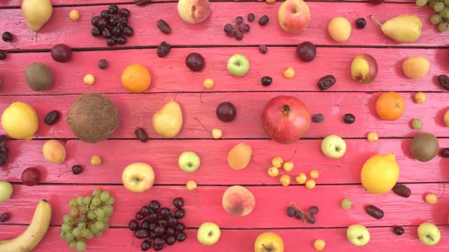 Fruits on pink ecological background. Top view. Fruits are located on pink wooden eco background. Men's hands take coconat from table. Here are: coconat, cherries, nectarines, apples, peaches.