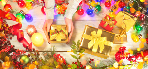Christmas scene. Person puts wrapped gift boxes on Xmas wooden background. Winter holiday backdrop. Top view, flatlay.
