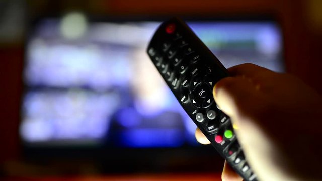 Man in front of the tv holding the remote control switching between chanels.
