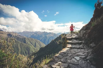 Crédence de cuisine en verre imprimé Machu Picchu A female hiker is walking on the famous Inca trail of Peru with walking sticks. She is on the way to Machu Picchu.