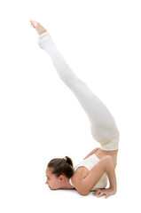 A young woman in a white suit performs acrobatic elements and yoga.