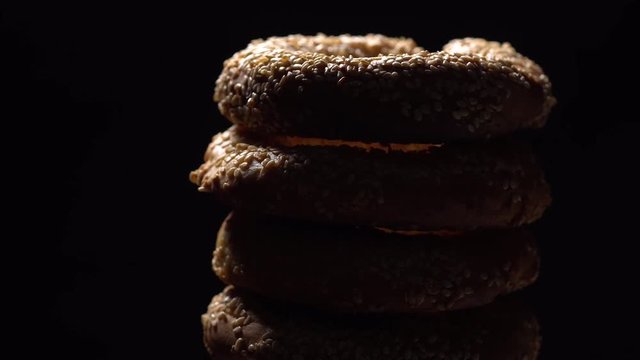 Fresh bagels with sesame seeds in rotation. Black background. Extreme closeup.