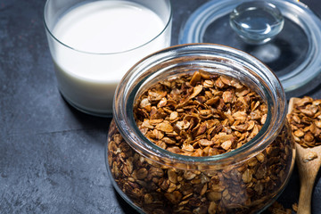 homemade baked granola in a glass jar and glass of milk