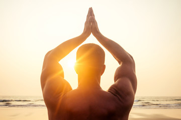 Man standing in yoga pose on ocean sunset paradise beach.Apollo athletic body, muscles