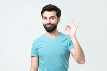 Gesturing OK sign. Cheerful hispanic young man in t-shirt showing approving sign. Good choice concept