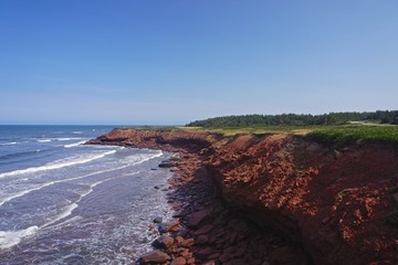 Obraz premium Prince Edward Island, Canada: A red sandstone beach under a clear blue sky on the north shore of Prince Edward Island, in the Gulf of St. Lawrence.
