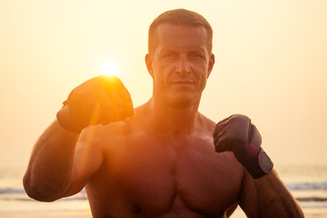 Strong boxer shirtless coach during kickboxing exercise with trainer in boxing gloves at...
