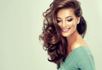 Photo sur Plexiglas Salon de coiffure Belle fille modèle avec de longs cheveux ondulés et brillants. Femme brune avec une coiffure frisée