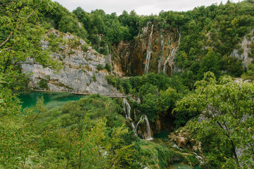 Travel to Croatia. Plitvice Lakes is a popular Croatian national park of incredible beauty. Photo of a favorite point among tourists - a stunning waterfall surrounded by greenery