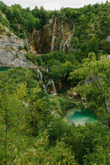 Plakat Travel to Croatia. Plitvice Lakes is a popular Croatian national park of incredible beauty. Photo of a favorite point among tourists - a stunning waterfall surrounded by greenery