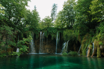 Travel to Croatia. Plitvice Lakes is a popular Croatian national park of incredible beauty. Photo of a favorite point among tourists - a stunning waterfall surrounded by greenery