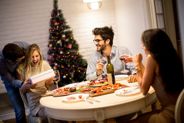 Young people celebrating Christmas and opening presents in the room