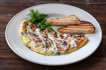 Vegetarian breakfast: scrambled eggs with mushrooms, greens and croutons on a white plate