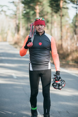 Training an athlete on the roller skaters. Biathlon ride on the roller skis with ski poles, in the helmet. Autumn workout. Roller sport. Adult man riding on skates.