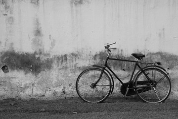 Fototapeta na wymiar Vintage Bicycle against Old Plastered Wall Background in Black & White