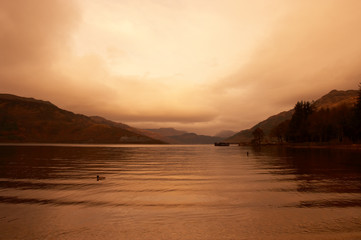 VIEW OF LOCH LOMOND AT TWILIGHT WITH MIST ON DISTANT HILLS FROM ROWARDENNAN LODGE STIRLING SCOTLAND