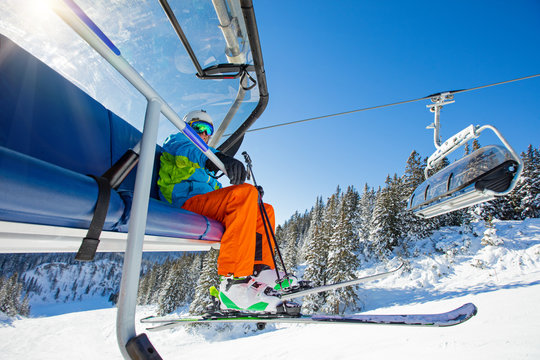 Skier sitting at ski chair lift.