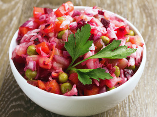 Closeup. Fresh homemade Beetroot salad Vinaigrette in a white bowl on wooden background. Traditional Russian food.Vegetarian food.