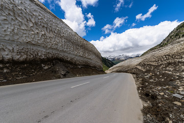 Turn of Nufenenpass pass road in spring inbetween the walls of snow, Switzerland