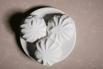 Three delicious sweet dessert white marshmallows zephyr on a saucer close-up. Copy space