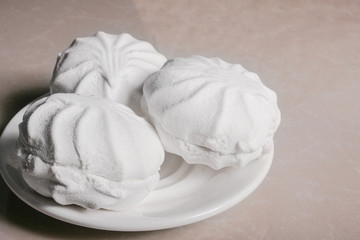 Three delicious sweet dessert white marshmallows zephyr on a saucer close-up. Copy space