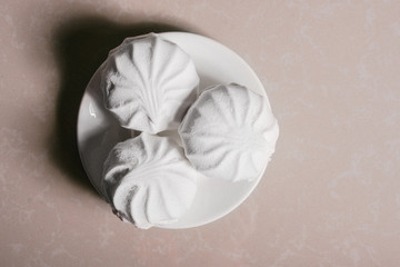 Three delicious sweet dessert white marshmallows zephyr on a saucer close-up. Copy space