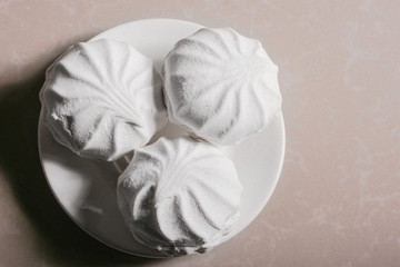 Three delicious sweet dessert white marshmallows zephyr on a saucer close-up. Copy space