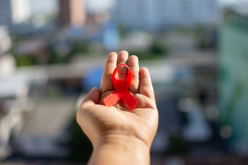 Red ribbon on hand with World Aids day concept.