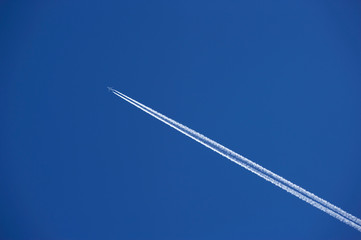 JET AIRLINER WITH EXHAUST VAPOUR TRAILS IN CLEAR BLUE SKY