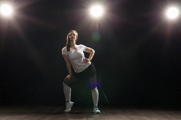 Fototapeta na wymiar Young woman dancer gymnastics exercise pose on dark background