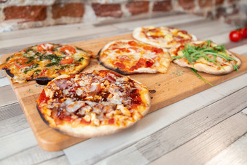 five pizzas on a wooden board on a wooden table