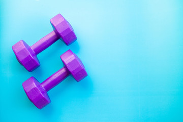 Fitness equipment dumbbells on color background. Flat lay.