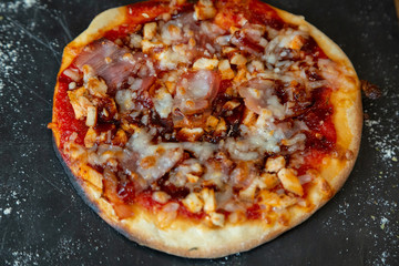 Close up of barbecue pizza on a blackboard garnish with flour