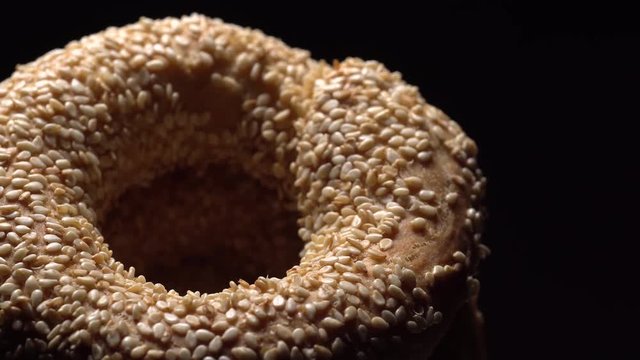 .Fresh bagels with sesame seeds in rotation. Black background. Extreme closeup.